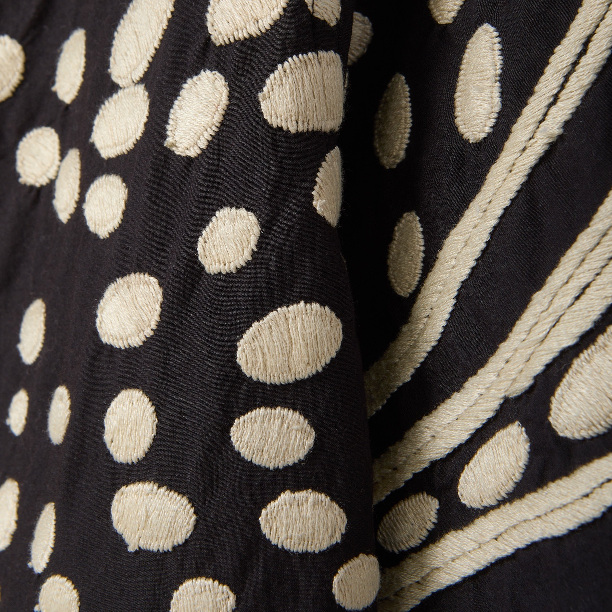 Close-up of black fabric with beige polka dot pattern