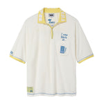 Cream terry cloth polo shirt with a yellow contrast collar, blue contrast stitching, embroidered “I was there in…” text, chest pocket with FIFA World Cup New York New Jersey patch, and FIFA World Cup sleeve patch.