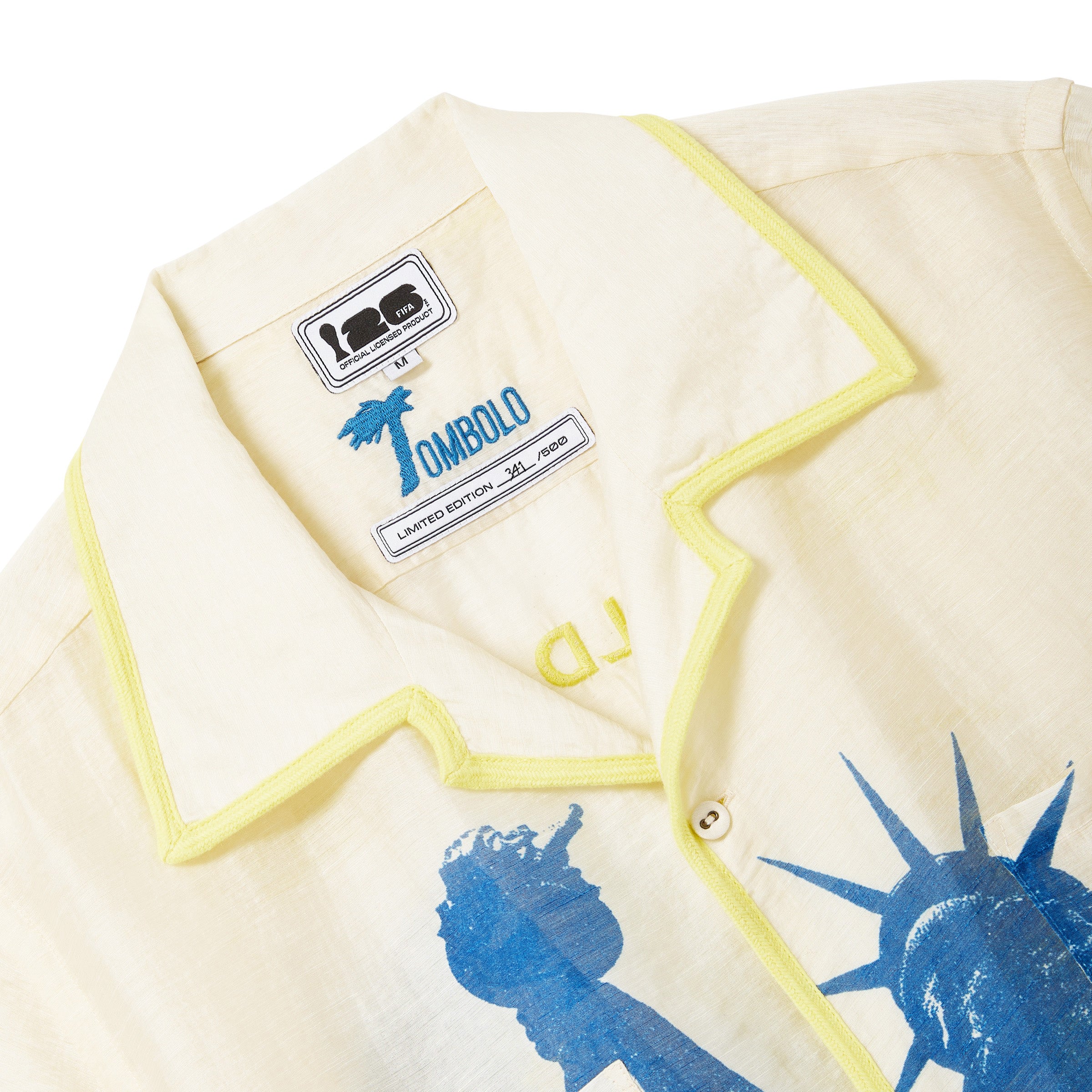 Close-up of interior labels on beige camp collar shirt with yellow contrast trim. 