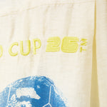 Text 'CUP 26' embroidered on beige fabric. 