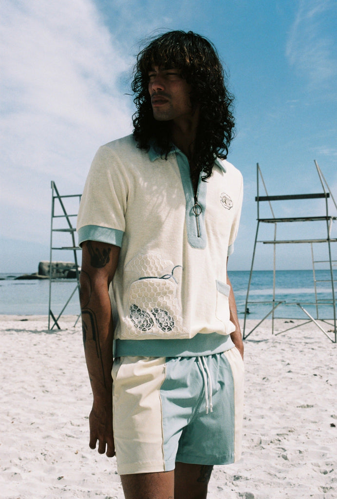 man wearing full matching oyster set on the beach looking off to his right