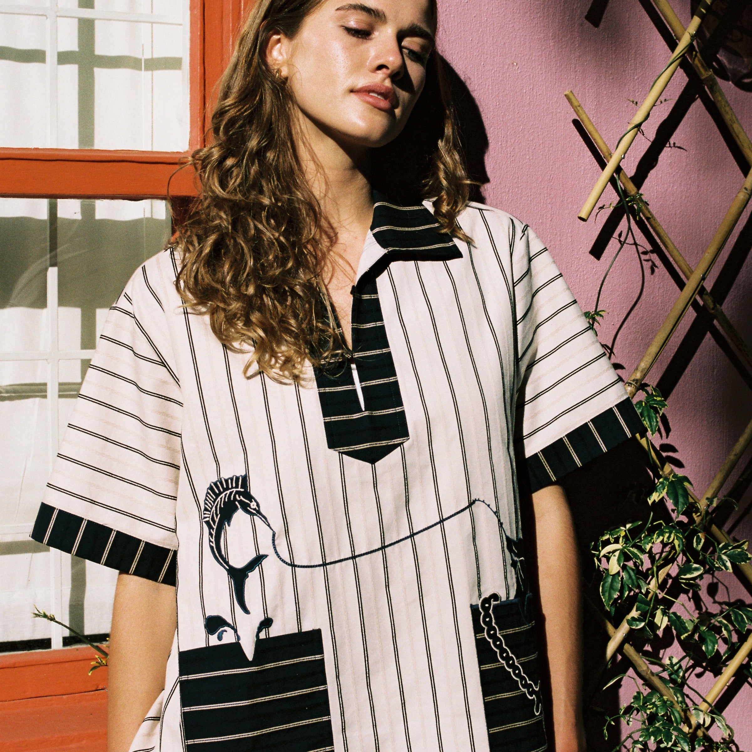 female model wearing Tombolo striped pop-over shirt looking to the right