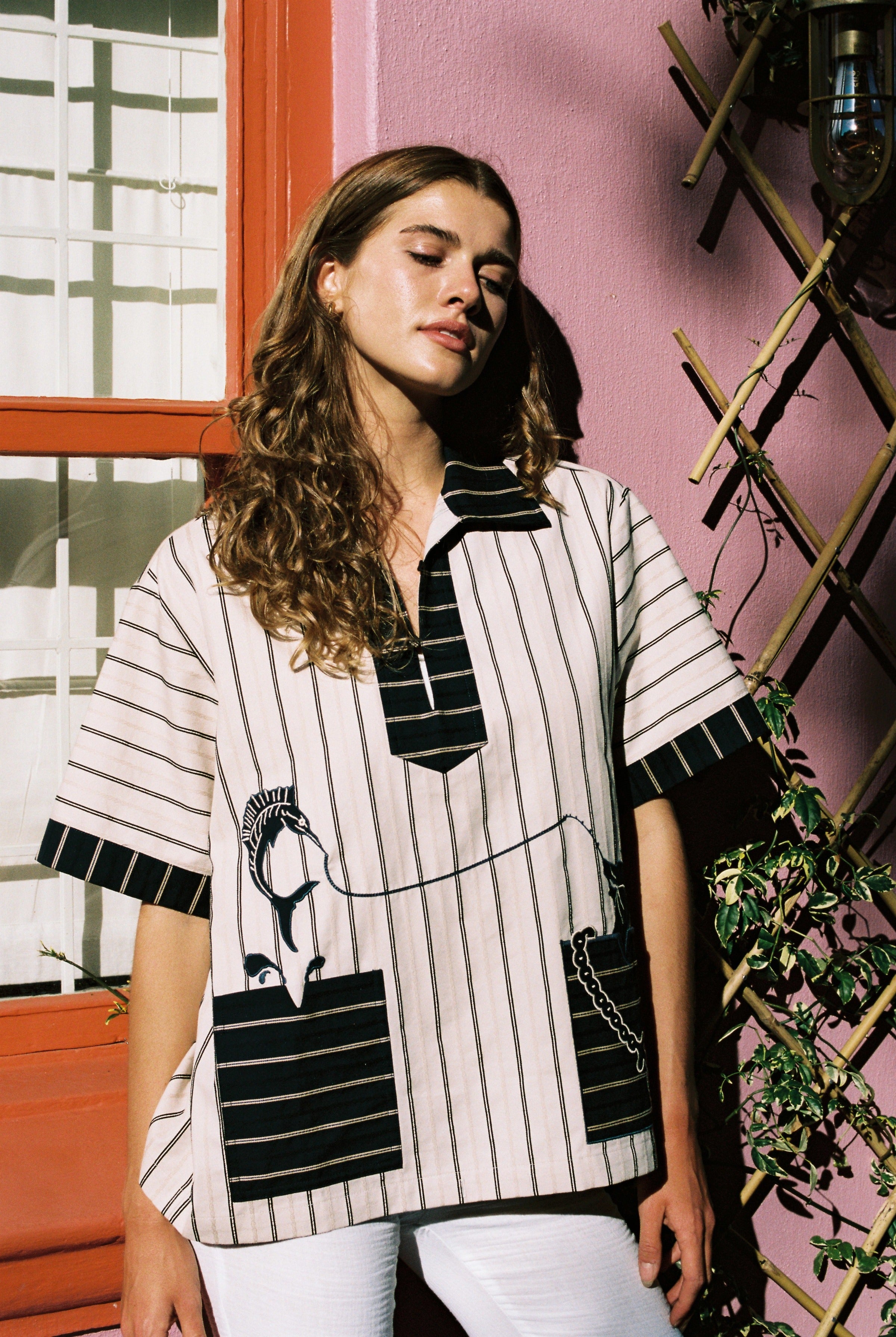 female model wearing Tombolo striped pop-over shirt looking to the right