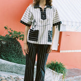 female model wearing Tombolo striped pop-over shirt with matching striped pants in front of a pink wall
