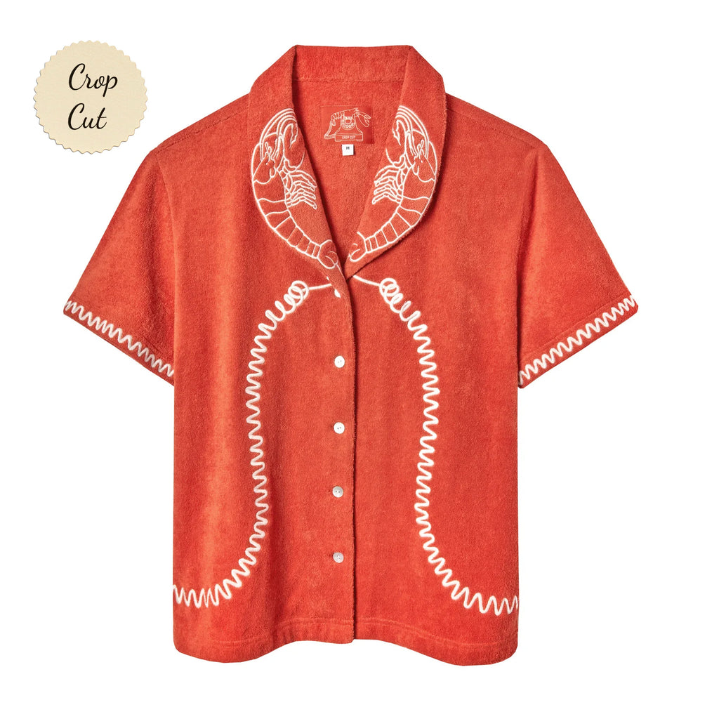 Short-sleeve terry cloth shirt in bright orange with white embroidered lobsters on the collar and coiled telephone cord detailing along the front and sleeves. Small sticker that reads "Crop Cut"