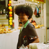 Female model wearing 'Picante' cabana shirt in a market. 