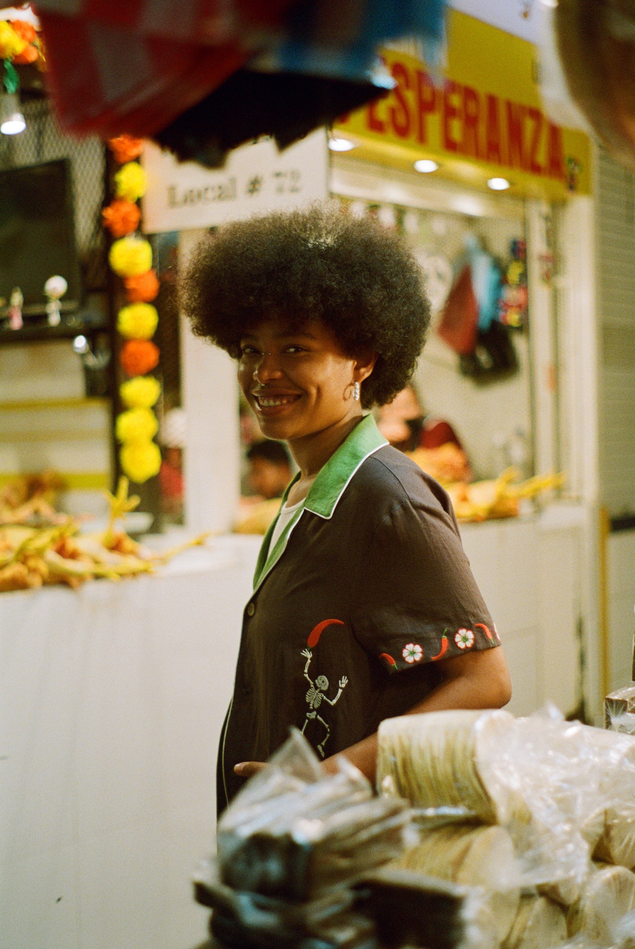 Female model wearing 'Picante' cabana shirt in a market. 