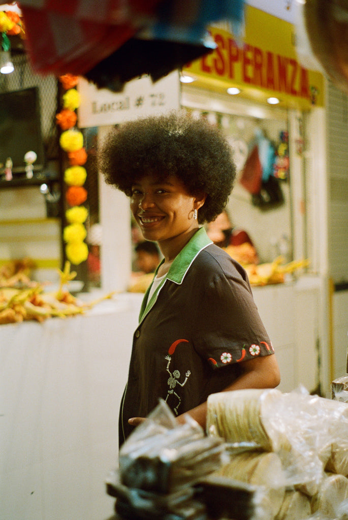 Female model wearing 'Picante' cabana shirt in a market. 