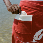 close up of red wrap skirt with shell peeking out of pocket