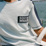 Close-up of a light blue cotton mesh shirt with navy sleeve panels and navy contrast stitching. The shirt features a navy chest pocket with white 'Boston Whaler' embroidery.