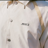 Close-up of a cream rain jacket with tan trim and 'Boston Whaler' logo.