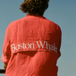 Back view of a person wearing a red button-up shirt with white embroidered text reading 'Boston Whaler' across the upper back.