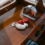 Set of boat keys with a red Mercury float and white Tombolo-branded whale keychain resting on a wooden boat console.