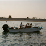 Small boat with a motor on a body of water during sunset.