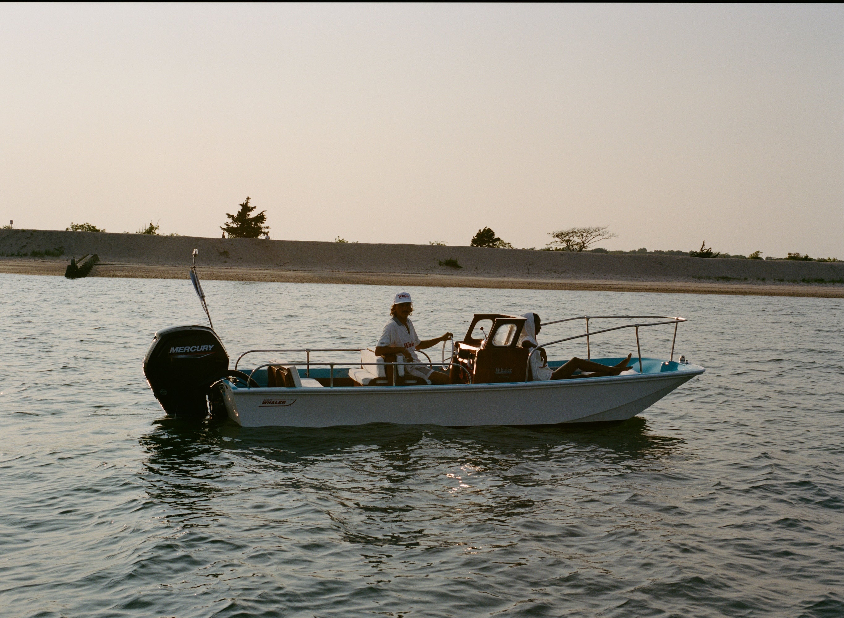 Small boat with a motor on a body of water during sunset.