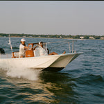 Two people on a boat in the water with a clear sky.