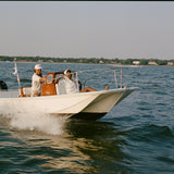 Two people on a boat in the water with a clear sky.