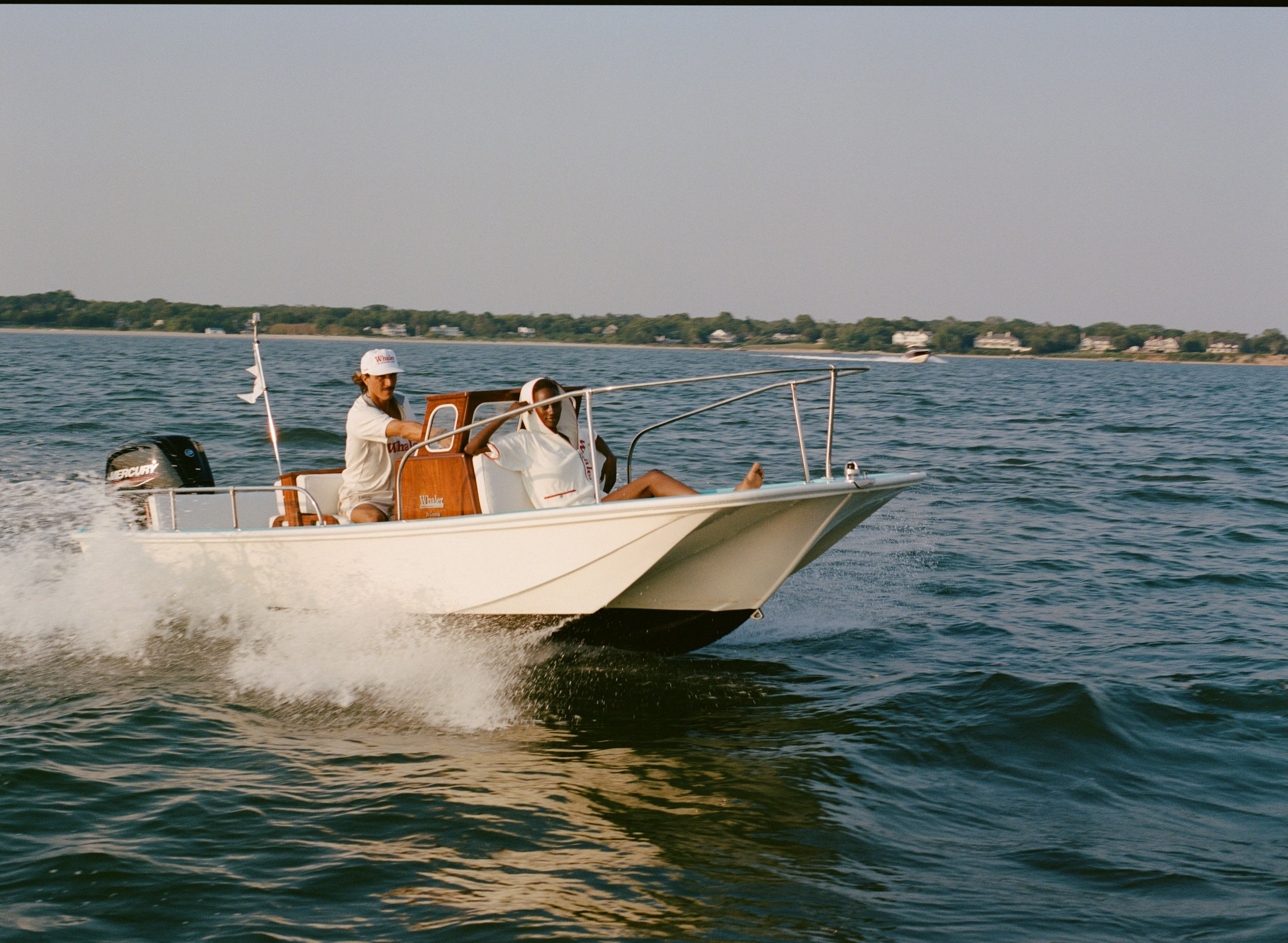 Two people on a boat in the water with a clear sky.