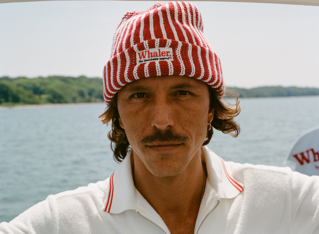 Man wearing red and white striped knit beanie with a 'Whaler' patch.