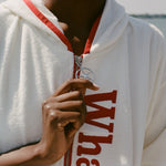 Close-up of woman holding the silver ship wheel zipper pull on the 'Whaler' beach towel top. 