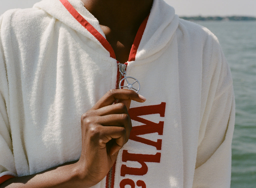 Close-up of woman holding the silver ship wheel zipper pull on the 'Whaler' beach towel top. 