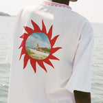 ChatGPT said:
Back of a white t-shirt with chain-stitched sunburst artwork framing a printed vintage photo of someone standing on a boat.