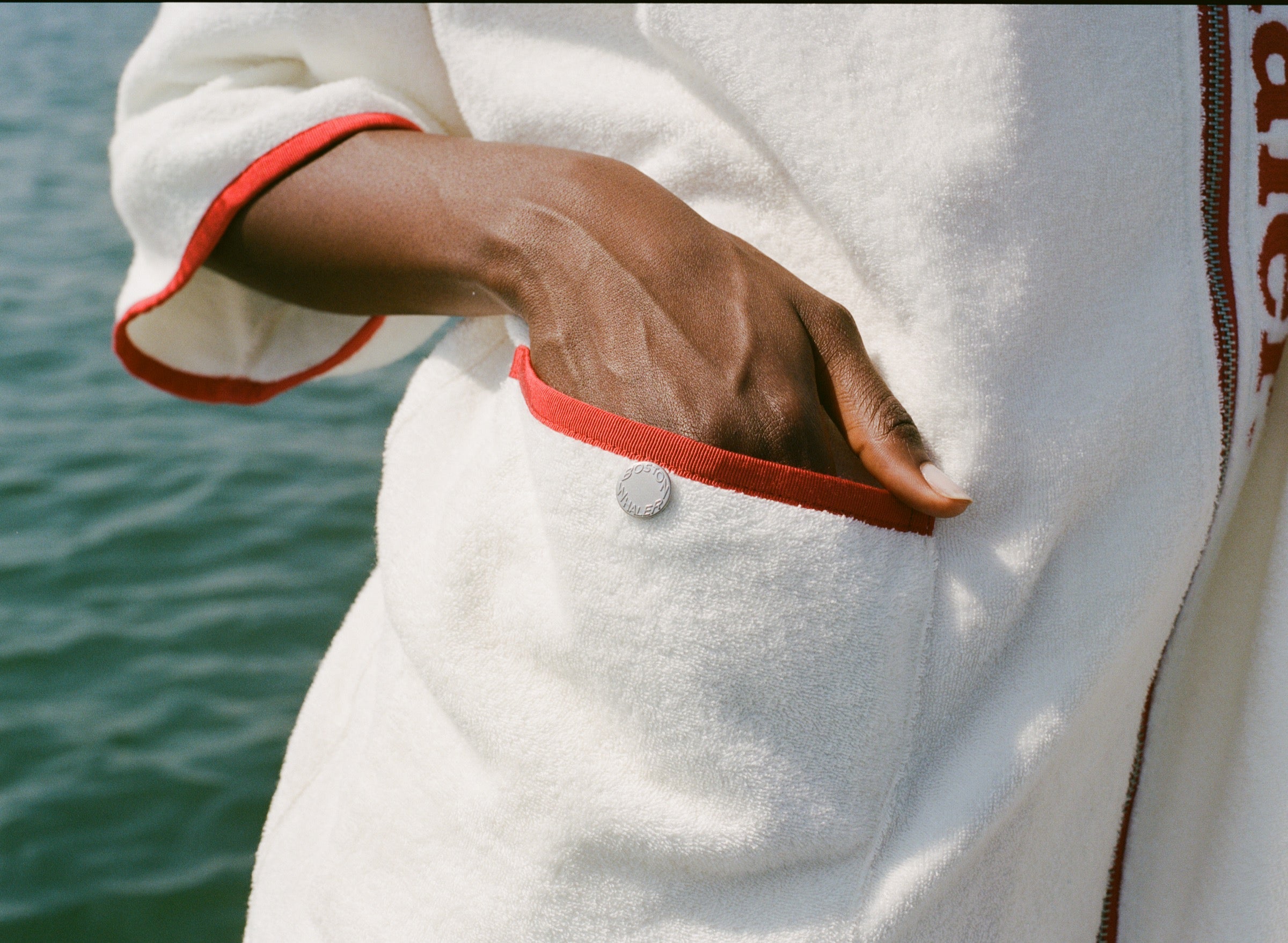 Close-up of woman's hand in front pocket of the hooded beach towel top. 