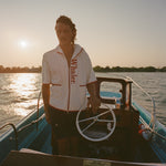 Man on boat wearing the 'Boston Whaler' 1961 Cabana, standing at the wheel.