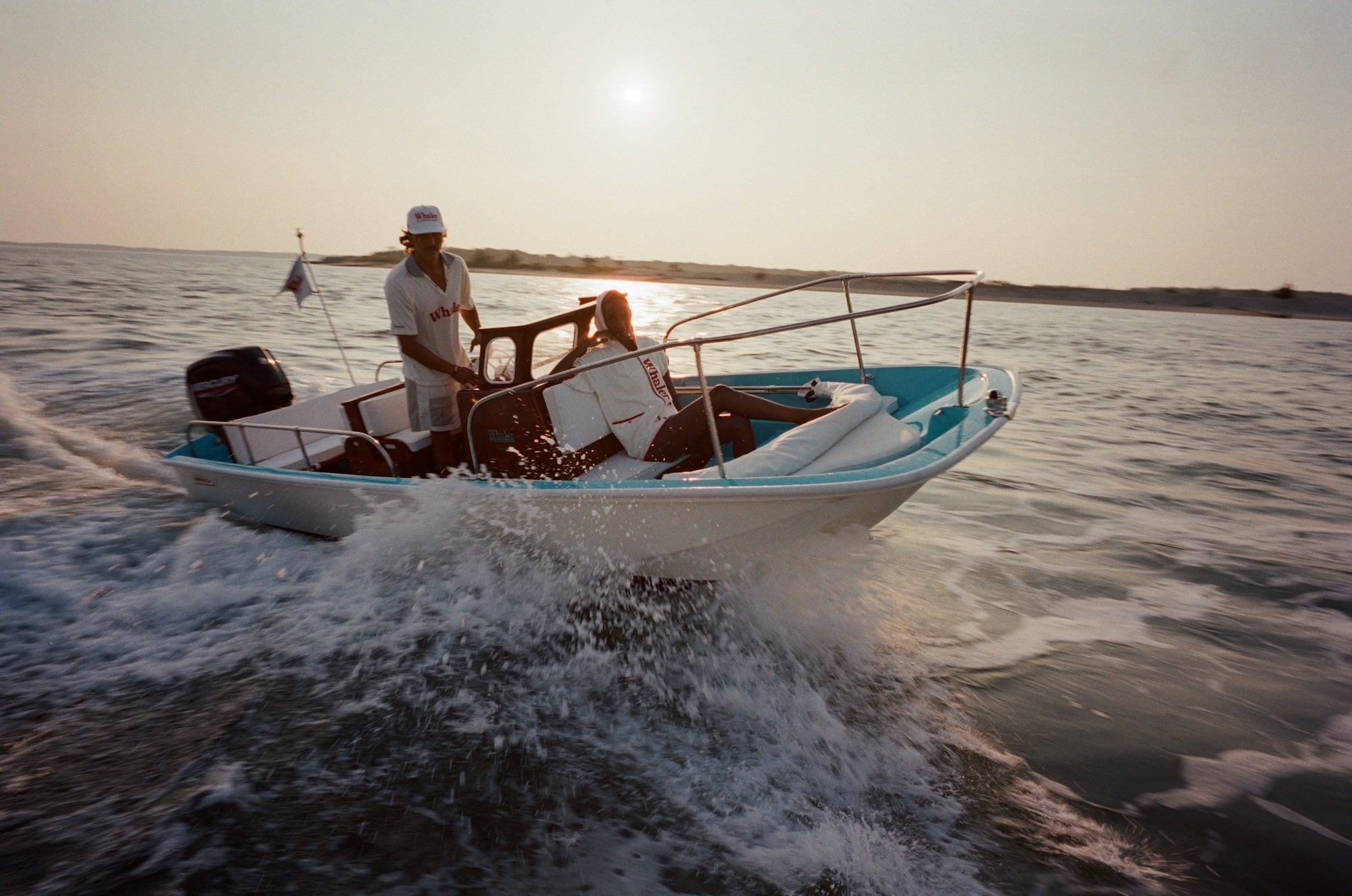 Two people on a boat in the water during sunset