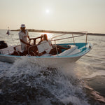 Two people on a boat in the water during sunset