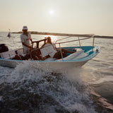 Two people on a boat in the water during sunset