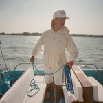 Man on a boat holding a rope with water and sky in the background, wearing the 'Boston Whaler' Foul Weather Jacket. 