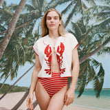 Female model with long blonde hair wearing the 'Better Half' Hand Towel Top with the top button buttoned, a red and white striped bikini bottom, shot against a background of palm trees, blue skies, and a beach. 