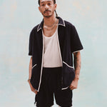 Male model with dreadlocks wearing the 'Standard Issue' Cabana Shorts (Midnight Blue) alongside a matching unzipped 'Standard Issue' Cabana in Midnight blue with a white, mesh tanktop underneath.