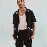 Male model with dreadlocks wearing the 'Standard Issue' Cabana Shorts (Midnight Blue) alongside a matching unzipped 'Standard Issue' Cabana in Midnight blue with a white, mesh tanktop underneath.