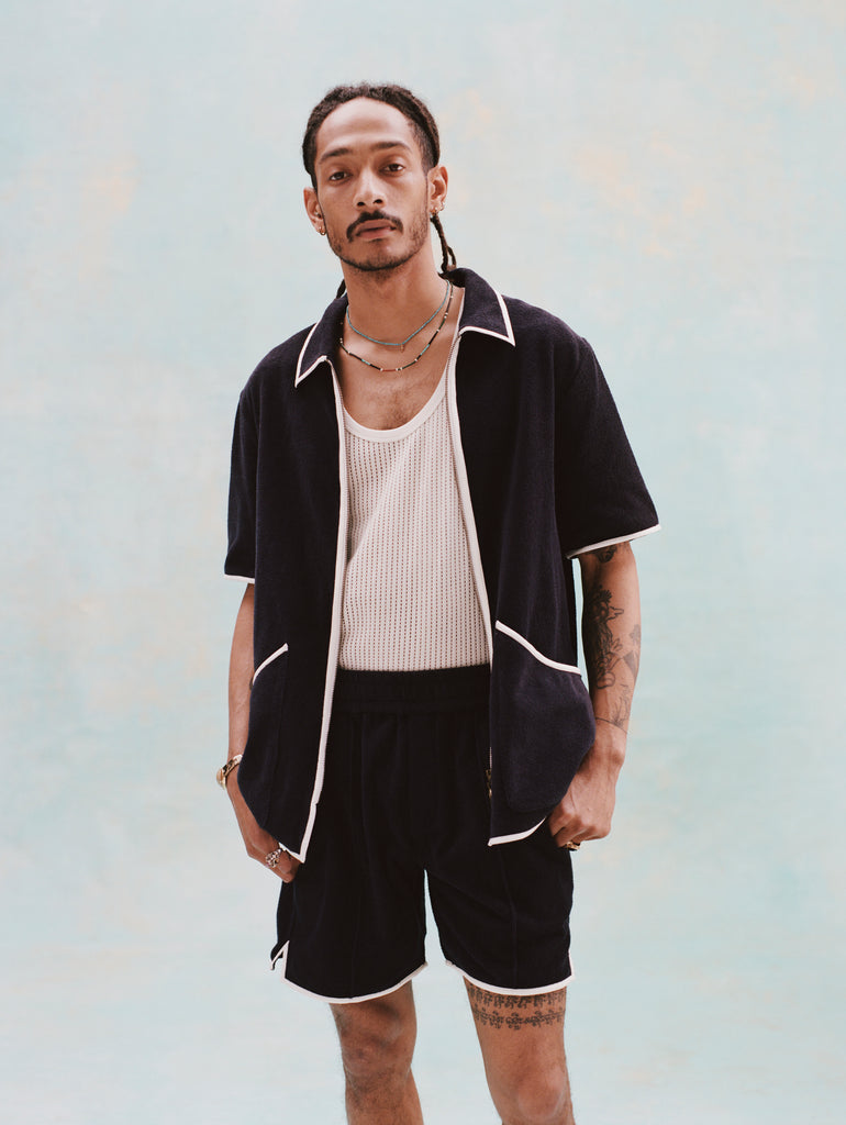 Male model with dreadlocks wearing the 'Standard Issue' Cabana Shorts (Midnight Blue) alongside a matching unzipped 'Standard Issue' Cabana in Midnight blue with a white, mesh tanktop underneath.