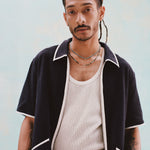 Male model with dreadlocks wearing the 'Standard Issue' Cabana (Midnight Blue) fully unzipped with a white tank top beneath it, and matching 'Standard Issue' Shorts in midnight blue, all shot on a white background.