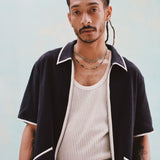 Male model with dreadlocks wearing the 'Standard Issue' Cabana (Midnight Blue) fully unzipped with a white tank top beneath it, and matching 'Standard Issue' Shorts in midnight blue, all shot on a white background.