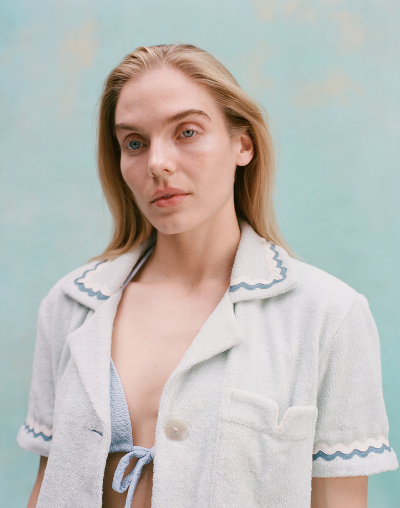 Female model with long blonde hair wearing the 'Rick Rack' Cabana ~ Crop Cut (Sky Blue) with a teal bikini top, shot on a light blue background.