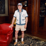 Older gentleman standing in the Explorer's Club entrance, wearing our 'Explorer's Club' Chum Cabana and our  'Explorers Club' 5-Panel Souvenir Cap.
