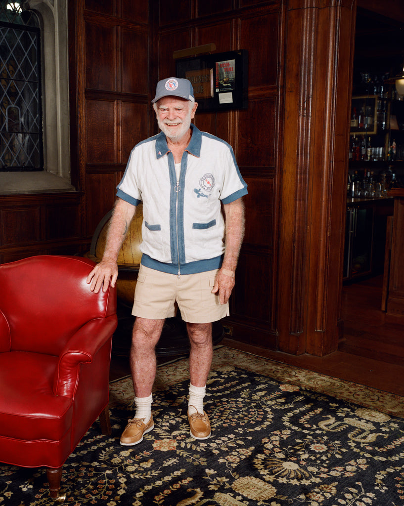Older gentleman standing in the Explorer's Club entrance, wearing our 'Explorer's Club' Chum Cabana and our  'Explorers Club' 5-Panel Souvenir Cap.