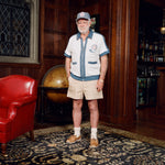 Older gentleman standing in the Explorer's Club entrance, wearing our 'Explorer's Club' Chum Cabana and our  'Explorers Club' 5-Panel Souvenir Cap.