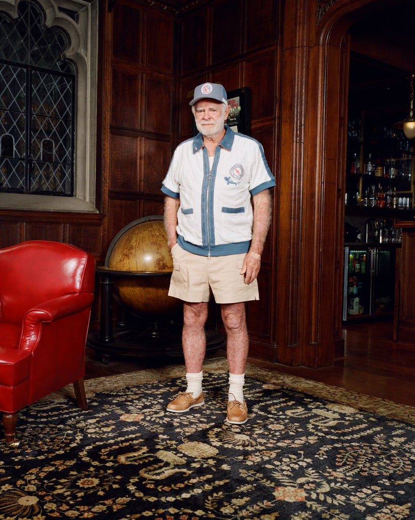 Older gentleman standing in the Explorer's Club entrance, wearing our 'Explorer's Club' Chum Cabana and our  'Explorers Club' 5-Panel Souvenir Cap.