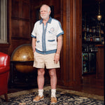Older gentleman standing in the Explorer's Club entrance, wearing our 'Explorer's Club' Chum Cabana and our  'Explorers Club' 5-Panel Souvenir Cap.