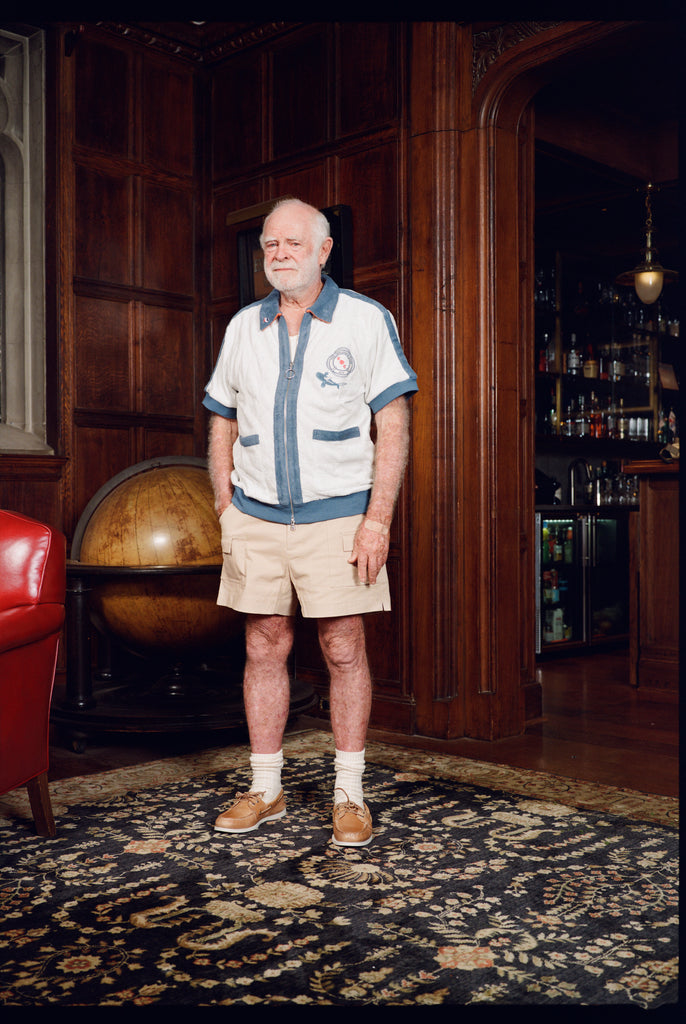 Older gentleman standing in the Explorer's Club entrance, wearing our 'Explorer's Club' Chum Cabana and our  'Explorers Club' 5-Panel Souvenir Cap.