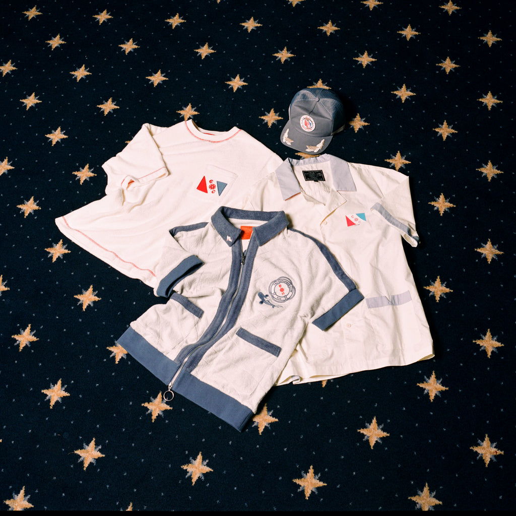 Image of all four 'Explorer's Club' x Tombolo items, featuring a Terry Tee, a Field Uniform, a TerryCloth Cabana and a Souvenir Cap.