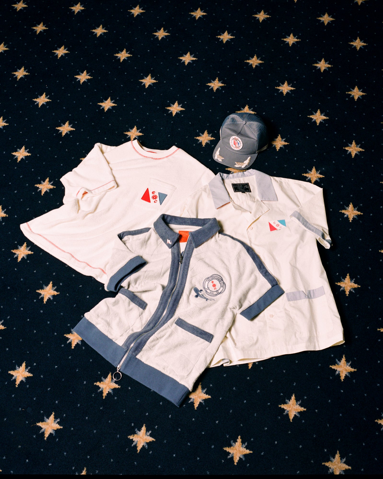 Image of all four 'Explorer's Club' x Tombolo items, featuring a Terry Tee, a Field Uniform, a TerryCloth Cabana and a Souvenir Cap.