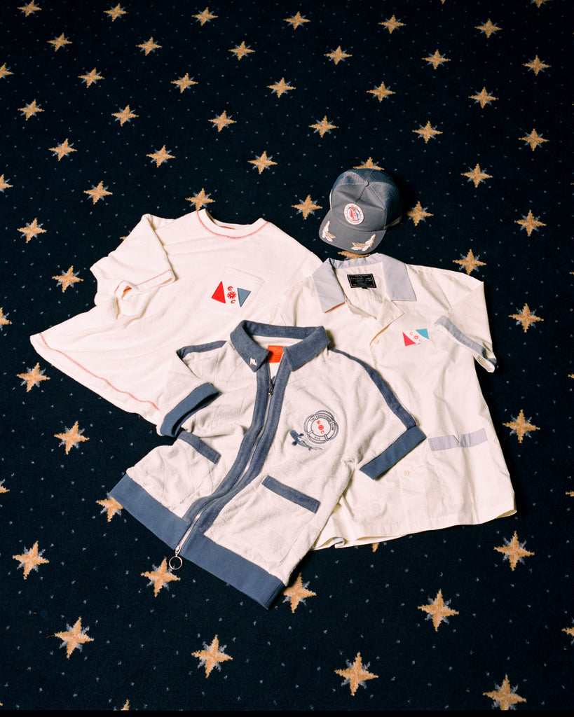 Image of all four 'Explorer's Club' x Tombolo items, featuring a Terry Tee, a Field Uniform, a TerryCloth Cabana and a Souvenir Cap.