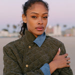 Woman looks at camera at sunset wearing quilted jacket