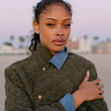 Woman looks at camera at sunset wearing quilted jacket